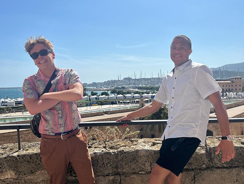 two students stand in front of a Spanish harbor