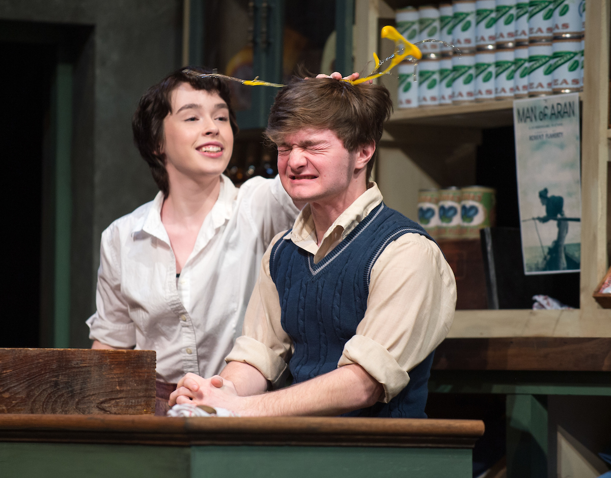 girl breaking egg over boys head in stage setting of rurual ireland