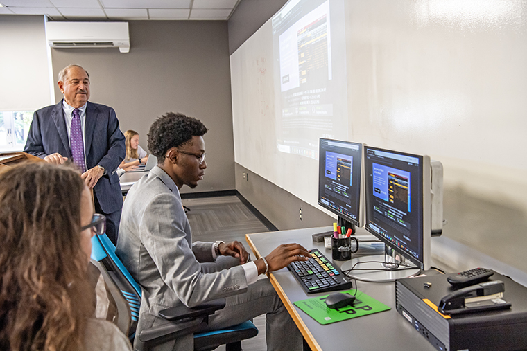 A student uses the new Bloomberg Terminal during class as Professor Richard Bookbinder looks on.