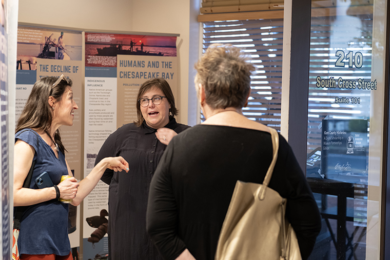 Education professor Sara Clarke-De Reza talks with attendees of a First Friday in the College's new exhibit space at 210 South Cross Street.