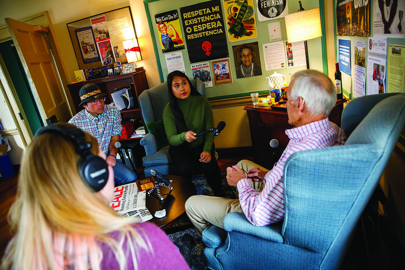 Three Washington College students record an oral history from a man in an armchair.