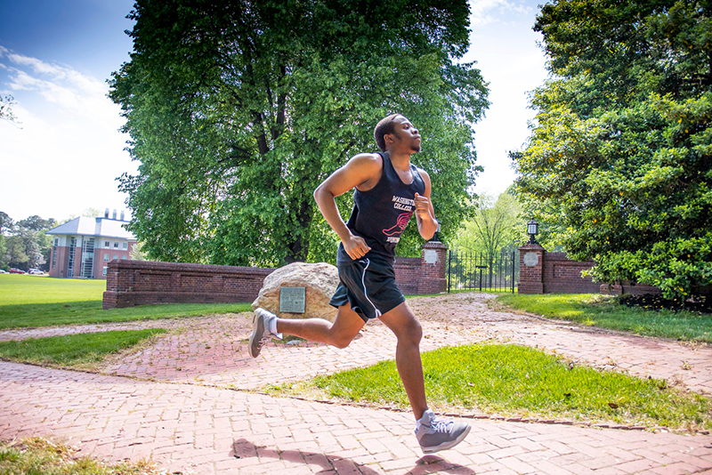 A student wearing a Washington College tank top runs past campus.