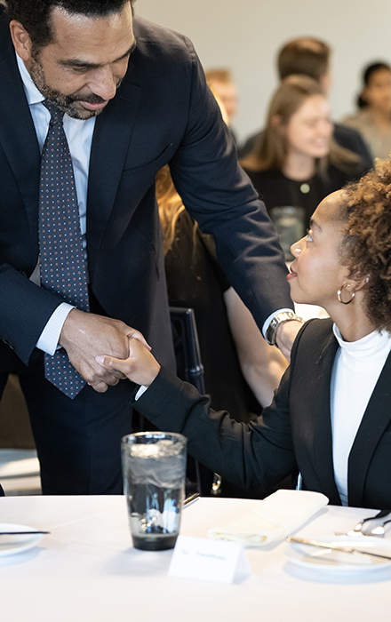 a student meets the keynote speaker at a business department dinner