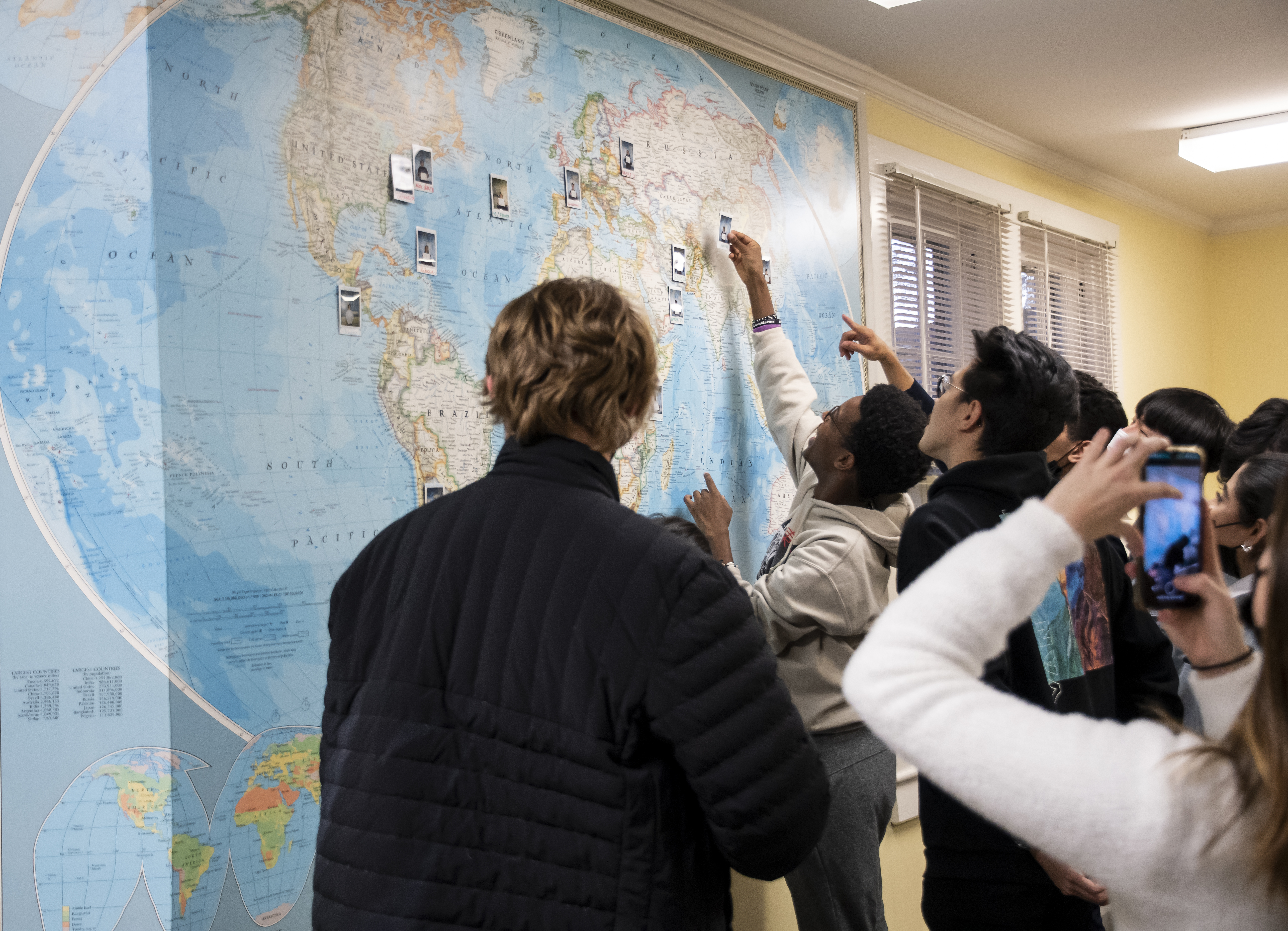 Members of WC's GEO look at a map with photos hanging on it