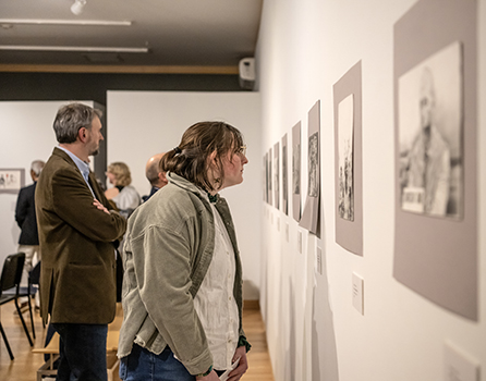 students and faculty examine drawings on the Kohl Gallery walls