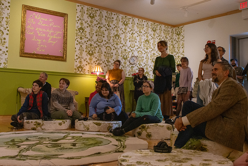 Attendees of the opening reception for The Rose Garden Green Room watch a video installation