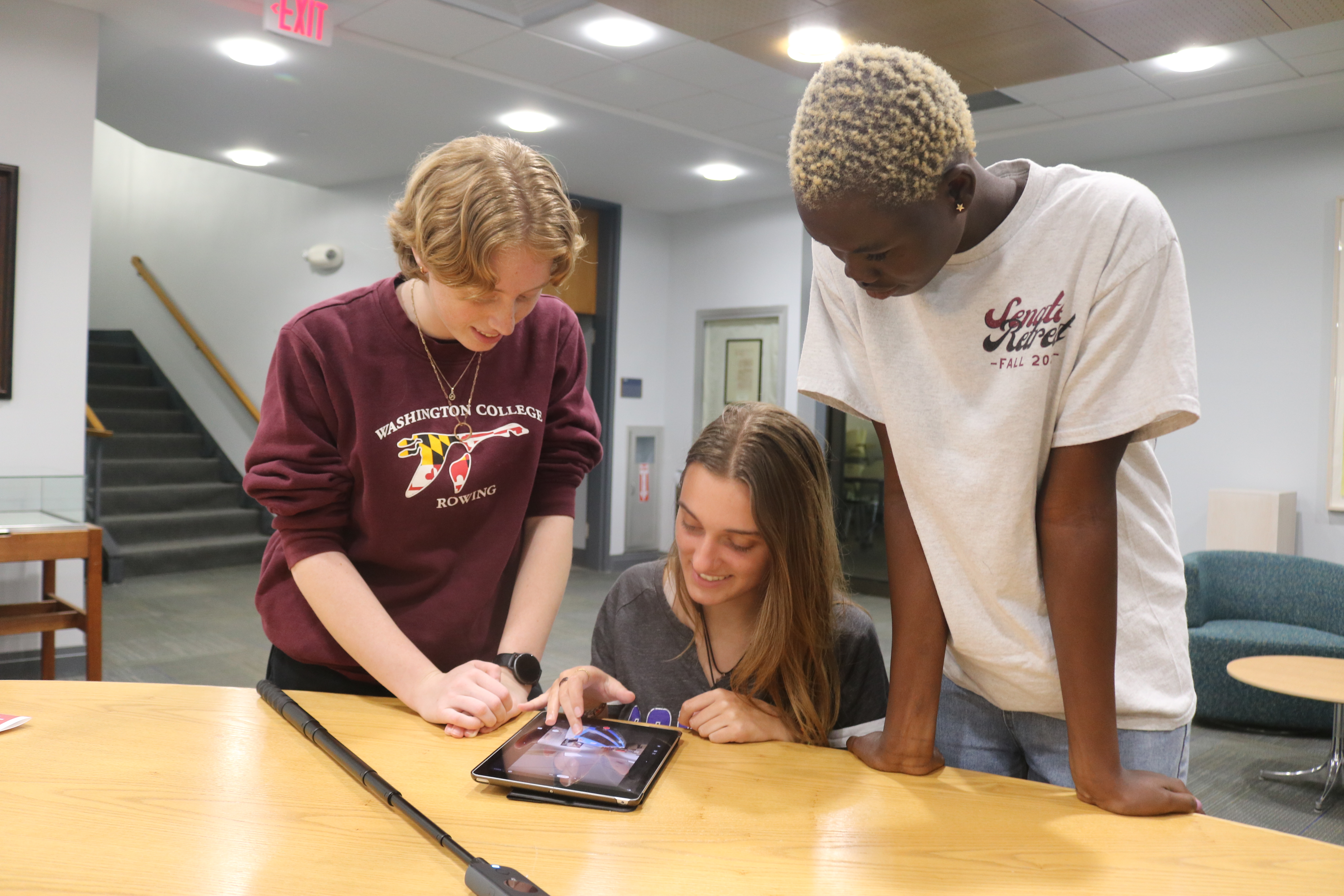 Three students gathered around an iPad