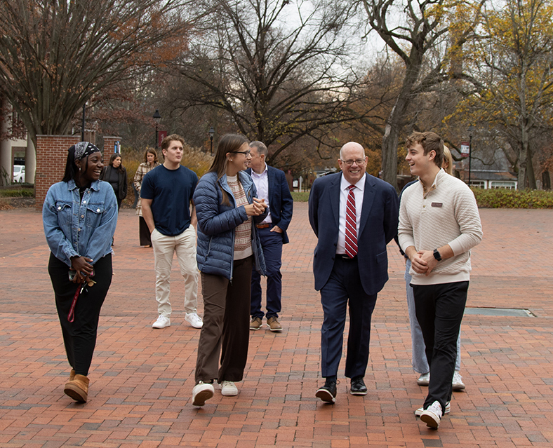 former maryland governor larry hogan walking across campus with washington students