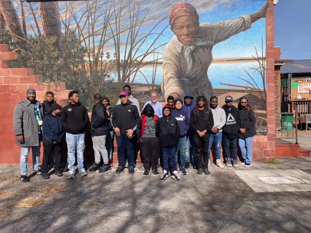 students stand in front of a mural of Harriet Tubman