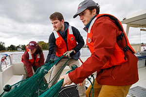 Students pulling a large net onto a boat