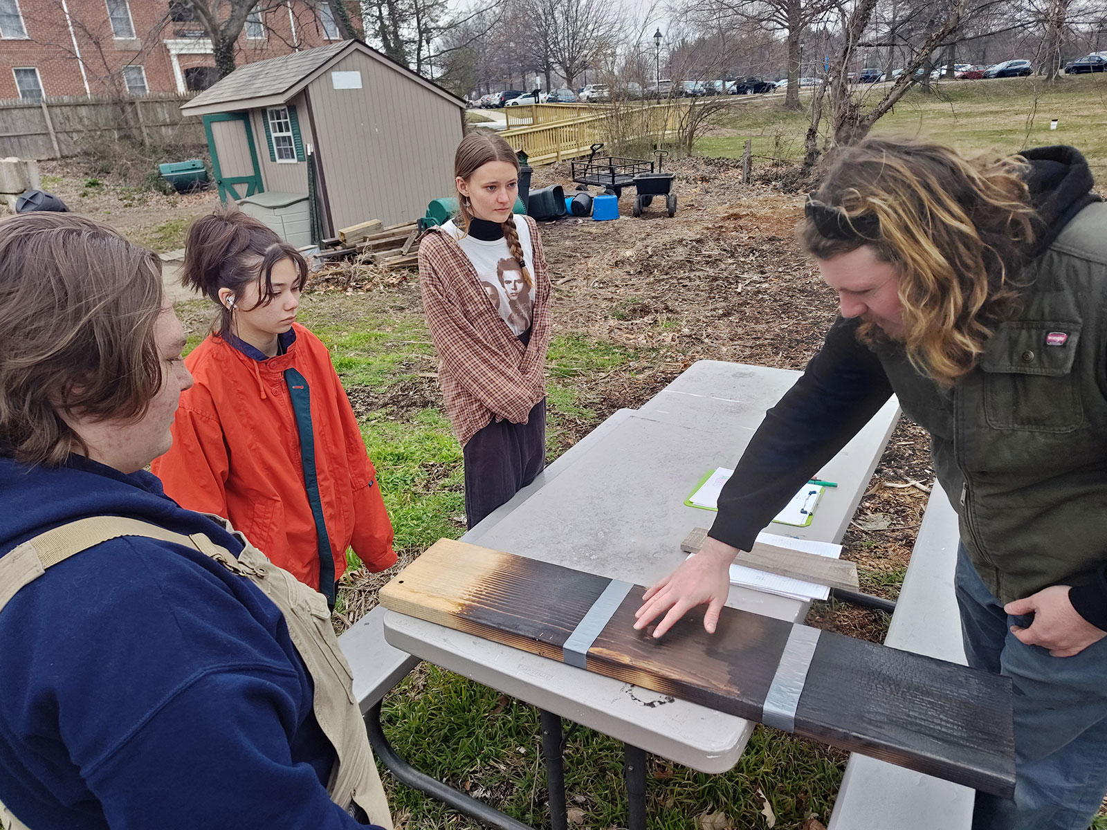 Students looking at burt wooden plank
