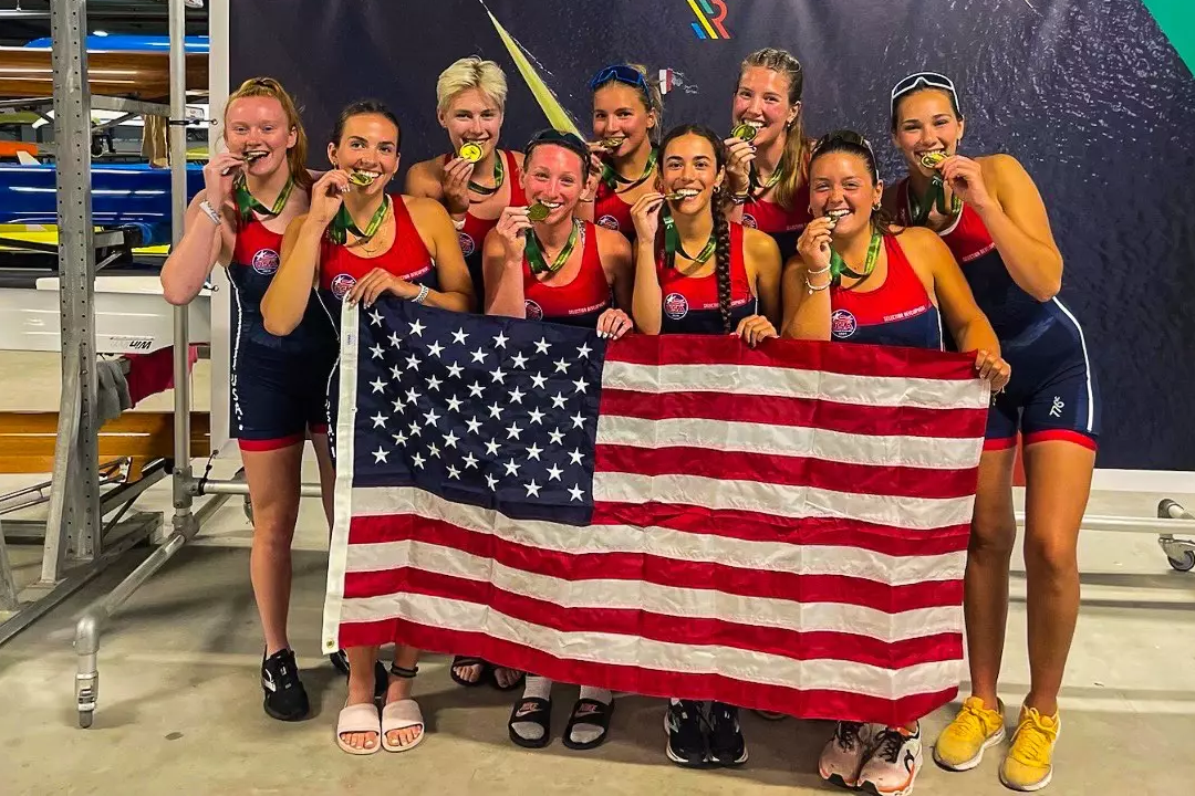 Jordan Hyde '25 and her teammates bite their gold medals behind an American flag.