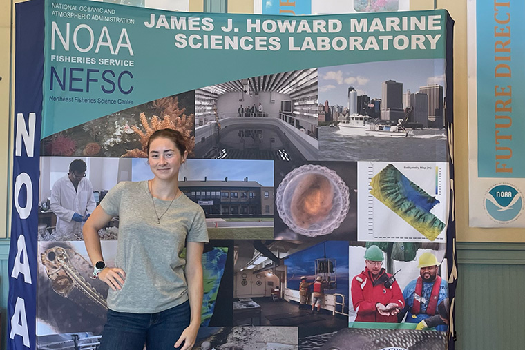 Peyton Baldwin '26 stands in front of a display about NOAA's Northeast Fisheries Science Center