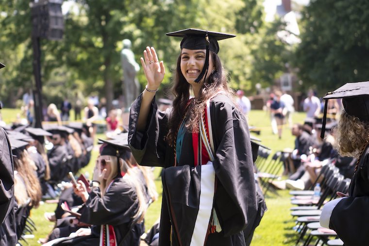 a graduate waves at the camera