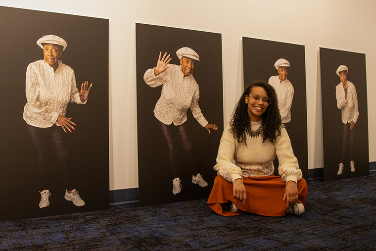Phaedra Michelle Scott sits in front of portraits of Norma Miller, subject of her play, Stompin' at the Savoy
