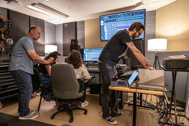 Andrew Wink '17 stands at a control panel on the right while music professor Ken Schweitzer talks to students in the Open Studio