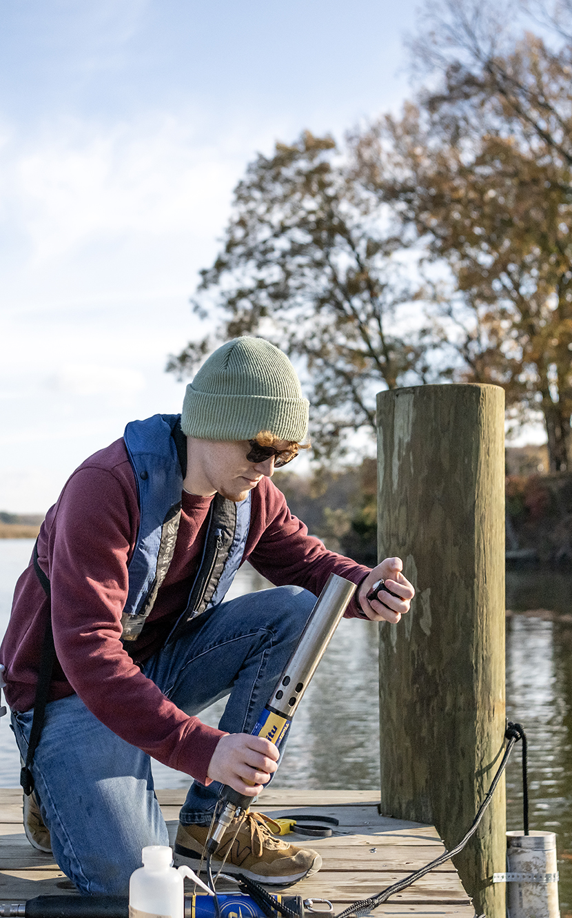 Peter Junkin '25 prepares water quality data collection equipment on a dock