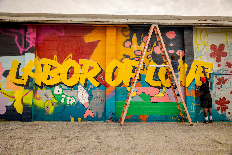 Mural artist Shelton Hawkins and Washington College student Evan Paddock (‘27) put the final touches on the “Labor of Love” mural currently on display at 800 High Street. Photo by Caroline J. Phillips. 
