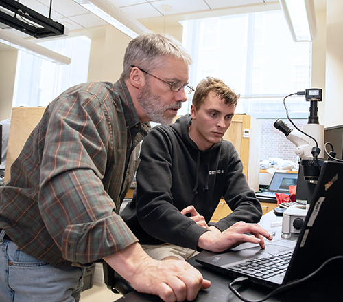 Professor Martin Connaughton watches a screen intently as a student operates the trackpad