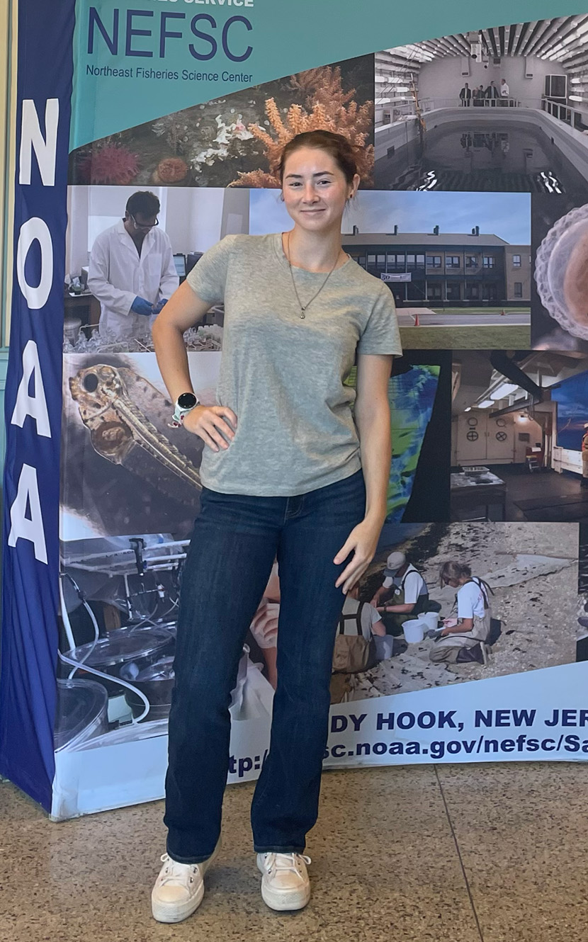 Peyton Baldwin '26 stands in front of a display about NOAA's Northeast Fisheries Science Center