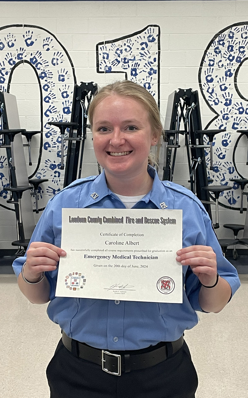 Caroline Albert holding up her EMT certificate