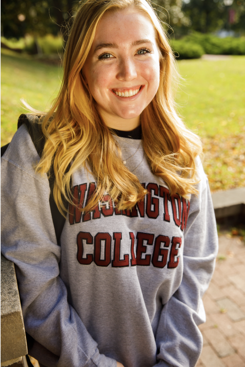 Haley, smiling and wearing a grey hoodie with "Washington College" in red lettering. 