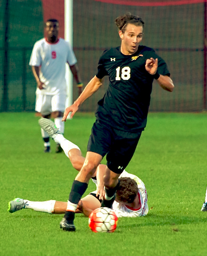 Skyler, wearing a Washington College Men's Soccer uniform kicks a soccer ball. 